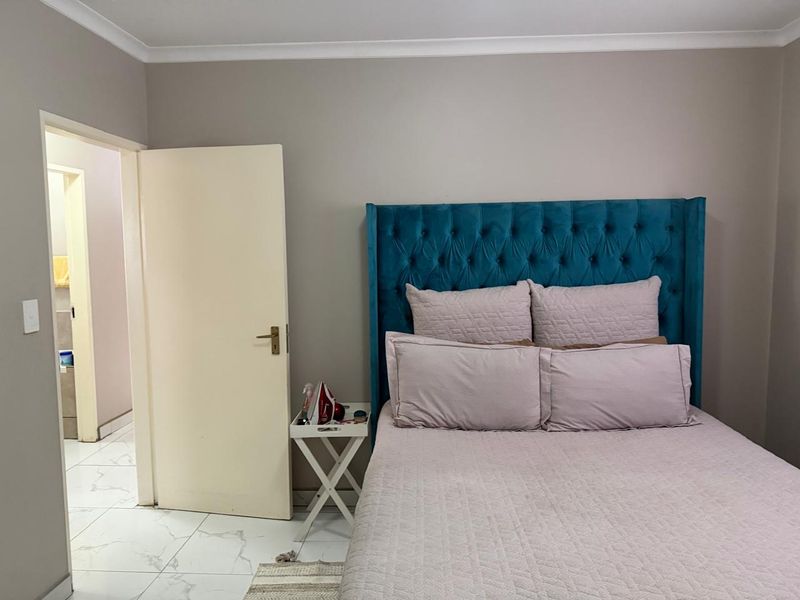 A well-maintained bedroom featuring neutral wall tones, tiled flooring, and a view into an adjacent bathroom.