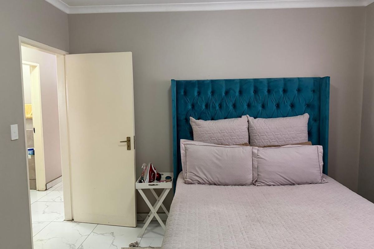 A well-maintained bedroom featuring neutral wall tones, tiled flooring, and a view into an adjacent bathroom.