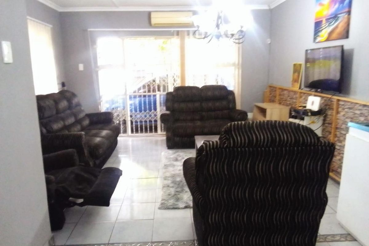 A living room featuring tiled flooring, a split-system air conditioner, and a sliding glass door with a security gate leading to the exterior.