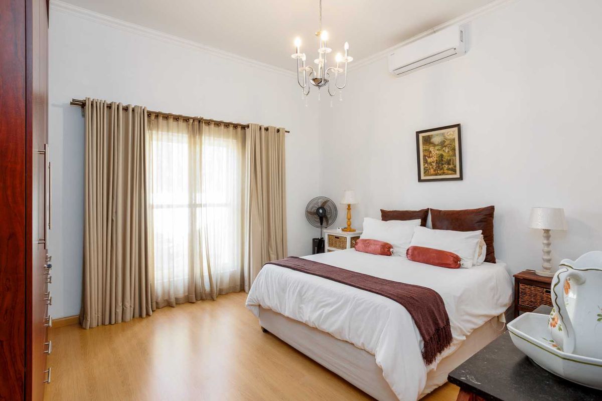 A well-maintained bedroom featuring laminate flooring, a built-in wardrobe, and a split-system air conditioner, offering a comfortable and functional living space.