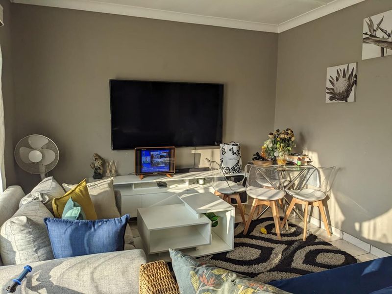 A compact living area featuring neutral wall tones, tiled flooring, and coving, providing a functional space for relaxation and dining.