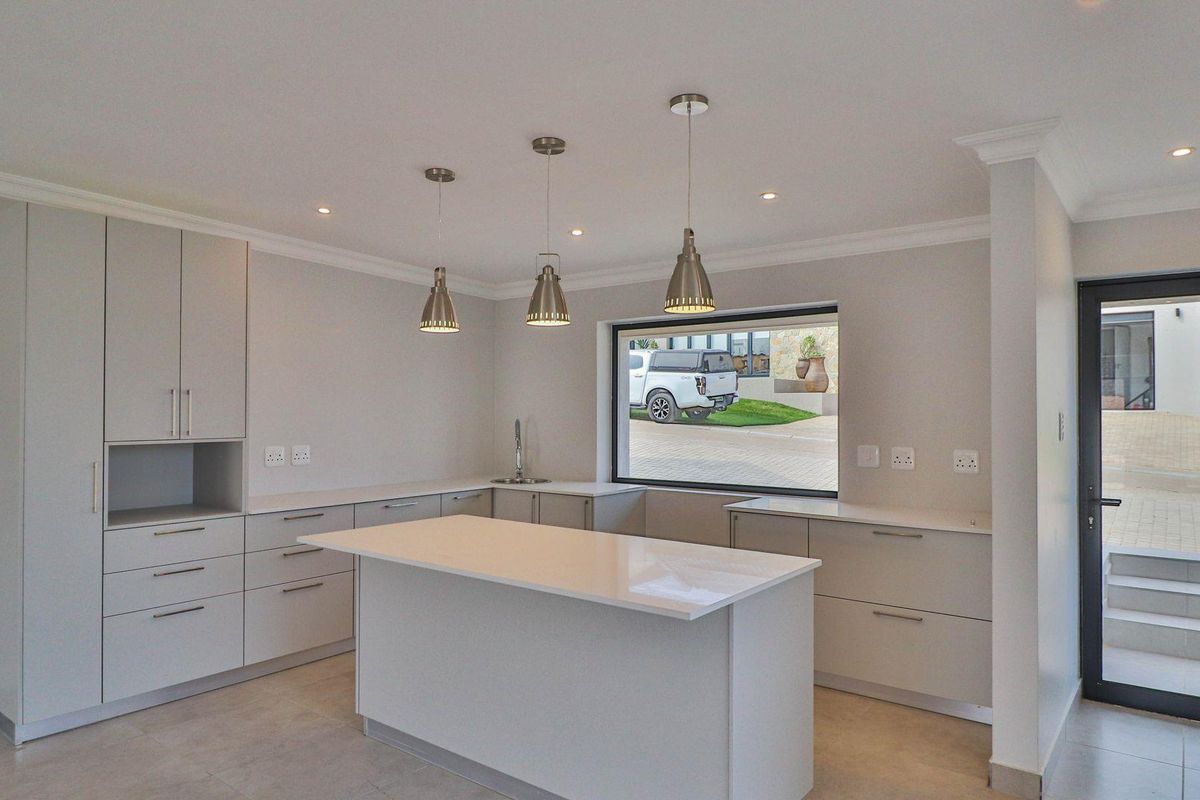 Modern kitchen featuring light grey cabinetry, a central island with stone countertops, recessed lighting, and direct access to the exterior.