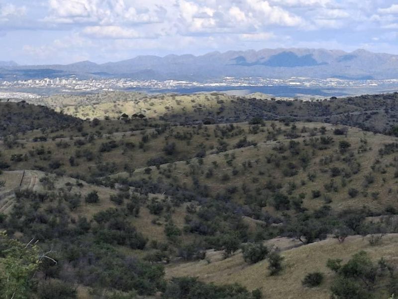 A scenic landscape view overlooking rolling hills and distant mountain ranges under a cloudy sky.