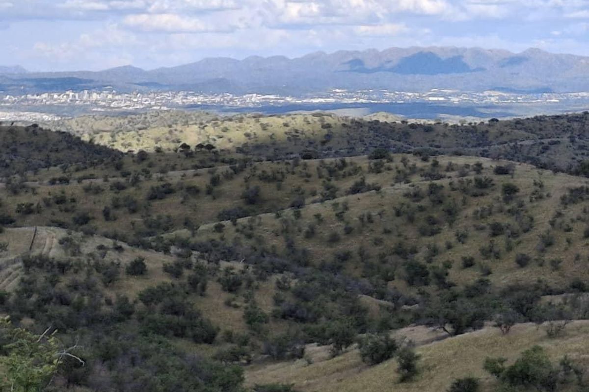 A scenic landscape view overlooking rolling hills and distant mountain ranges under a cloudy sky.