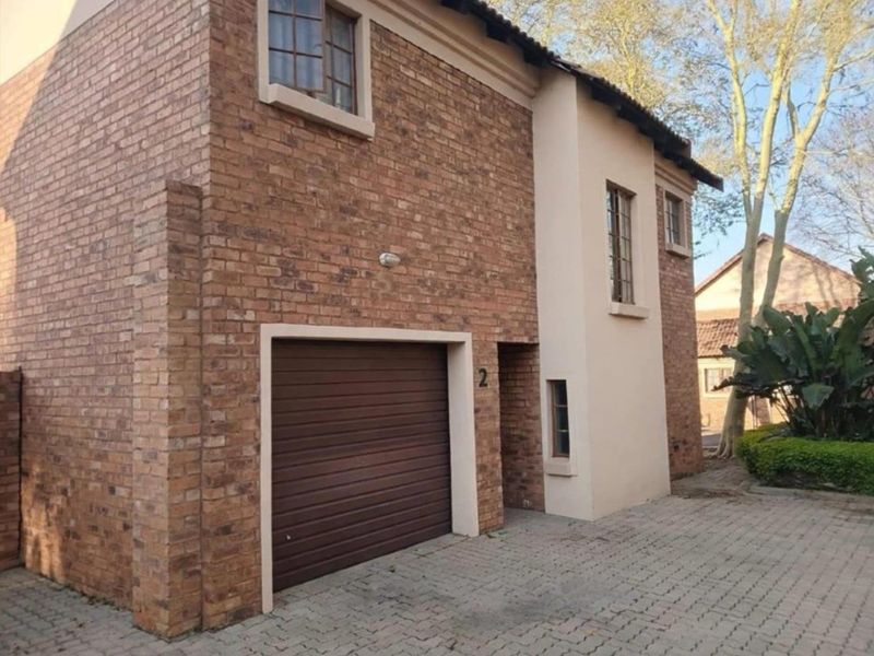 Front exterior view of a two-story apartment unit featuring a brick facade, integrated garage, and paved driveway access.