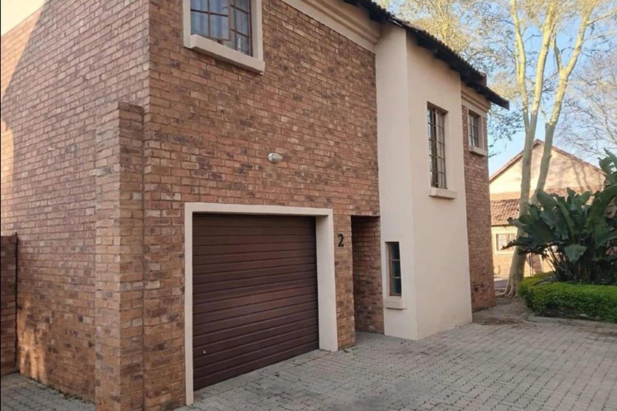 Front exterior view of a two-story apartment unit featuring a brick facade, integrated garage, and paved driveway access.