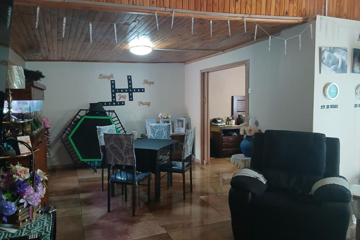 A living area featuring a timber-clad ceiling and tiled flooring, with an open doorway leading to an adjacent room.