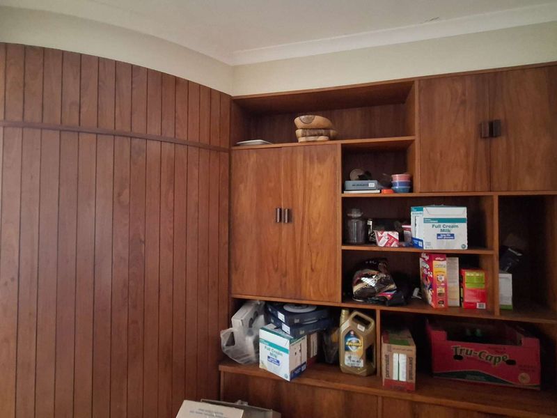A living area featuring extensive built-in wooden cabinetry and decorative wood wall paneling, providing ample storage space.