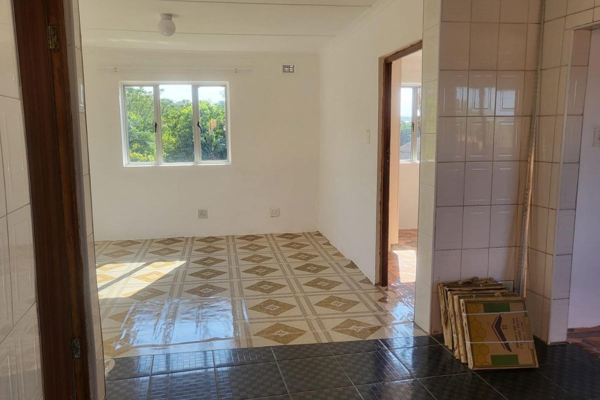 An empty living area featuring tiled flooring and natural light, currently undergoing minor renovations with spare tiles present.