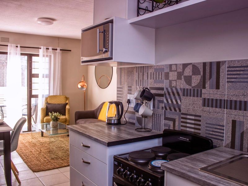 Open-plan kitchen and living area featuring modern cabinetry, a patterned tile backsplash, and direct access to an outdoor patio through sliding glass doors.