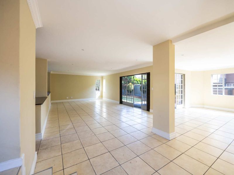 Spacious open-plan living area featuring neutral walls, ceramic tile flooring, recessed lighting, and large sliding glass doors providing access to the exterior.
