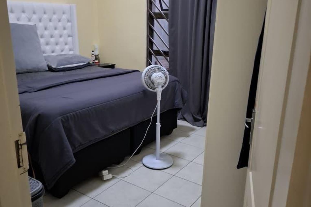 A functional bedroom featuring tiled flooring, a security gate on the window, and neutral wall finishes.