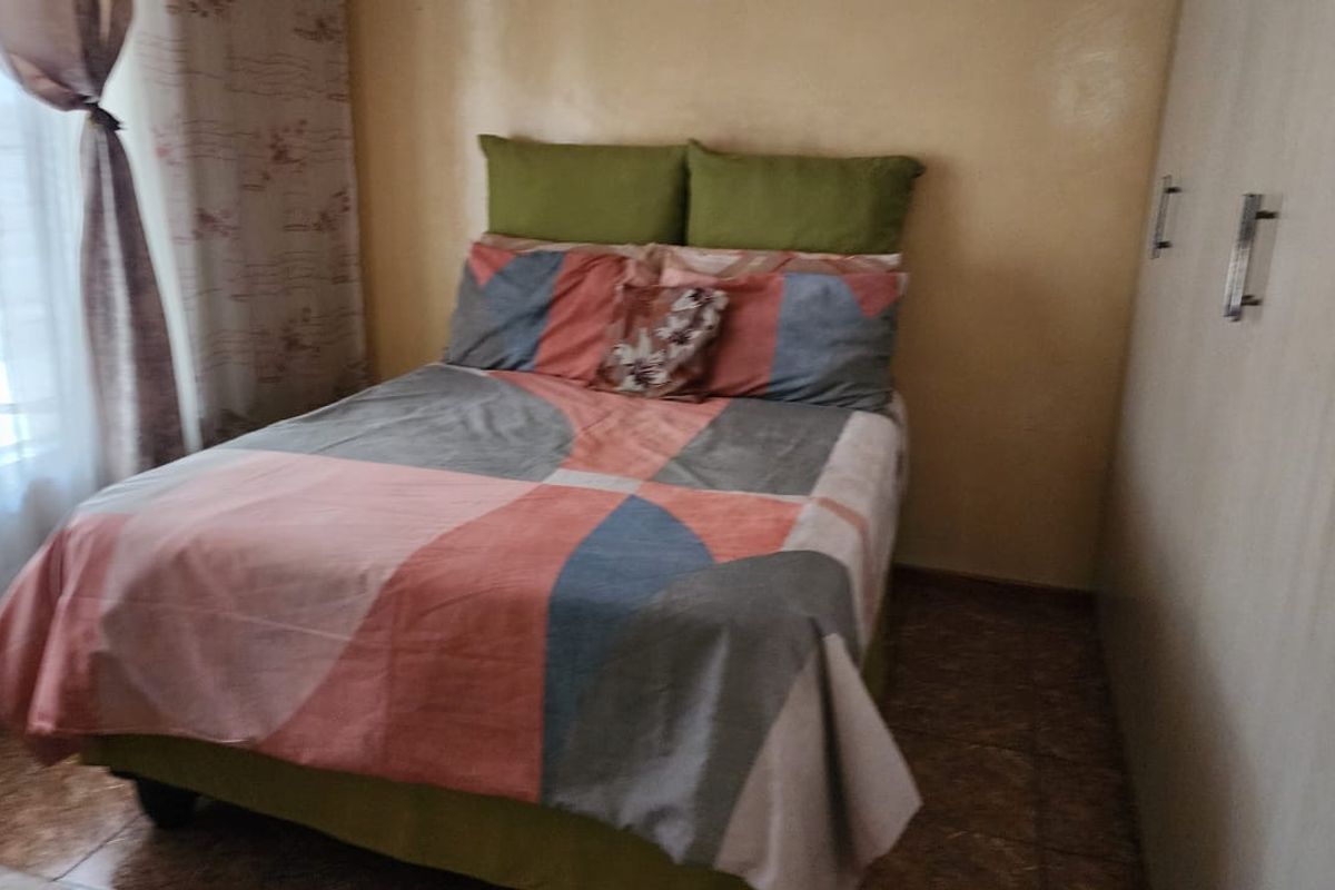 A functional bedroom featuring tiled flooring and a built-in wardrobe, providing essential storage space.