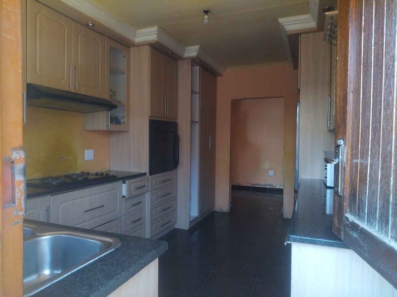 A functional kitchen featuring built-in cabinetry, granite countertops, a gas hob, and an integrated oven, with tiled flooring throughout.