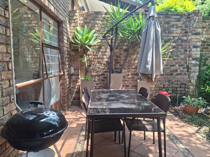 A private outdoor patio area featuring exposed brick walls and tiled flooring, providing a cozy space for outdoor dining and relaxation.