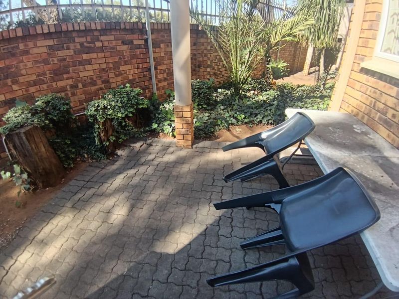 A paved outdoor patio area featuring a brick boundary wall and a structural support column, offering a private space for outdoor relaxation.