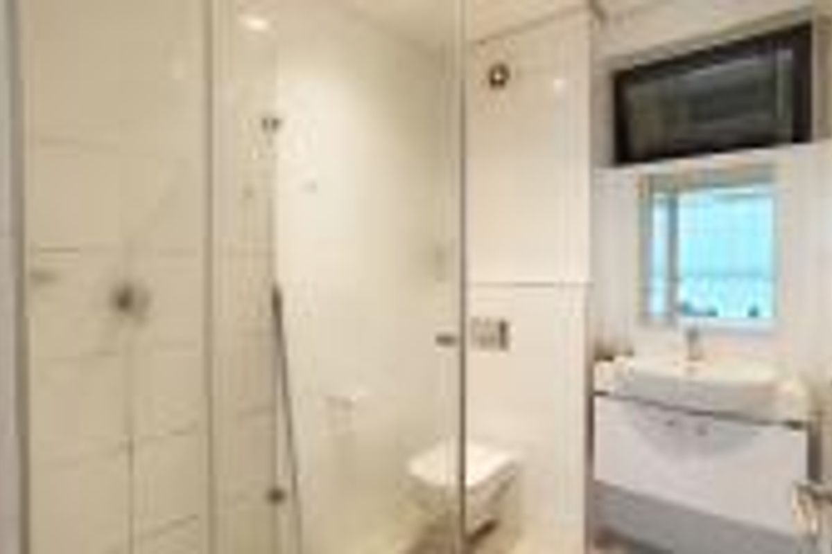 Modern bathroom featuring a glass-enclosed shower, wall-mounted toilet, and a sleek vanity unit with a basin.