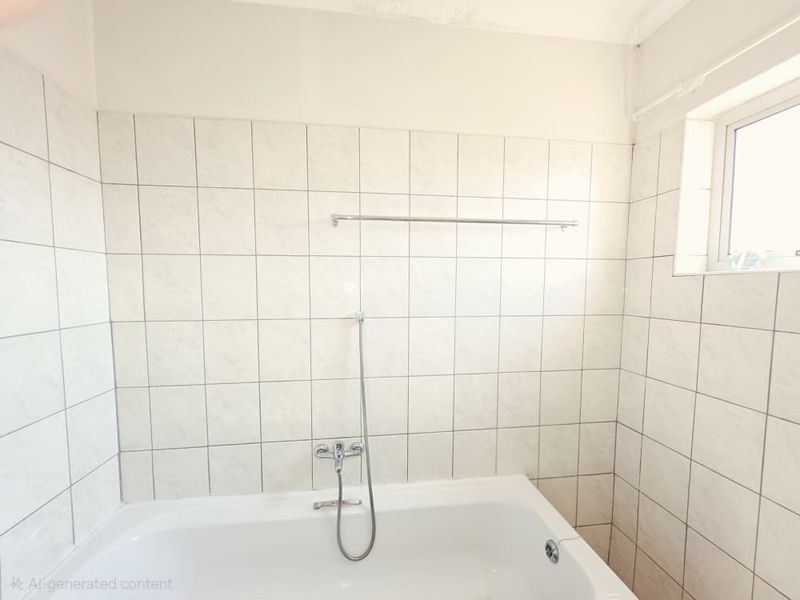 A functional bathroom featuring a bathtub with a shower mixer, tiled walls, and a window, requiring some cosmetic updates to the ceiling and grout.