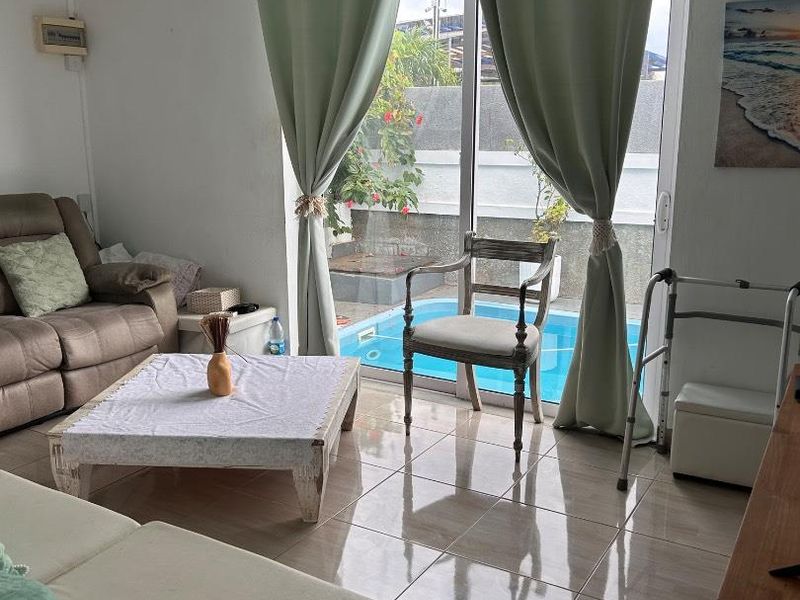 Living room featuring tiled flooring and sliding glass doors that provide direct access to an outdoor swimming pool area.