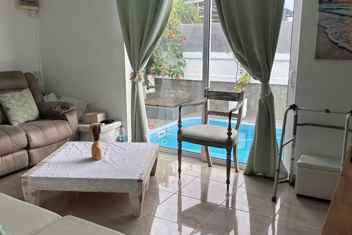 Living room featuring tiled flooring and sliding glass doors that provide direct access to an outdoor swimming pool area.
