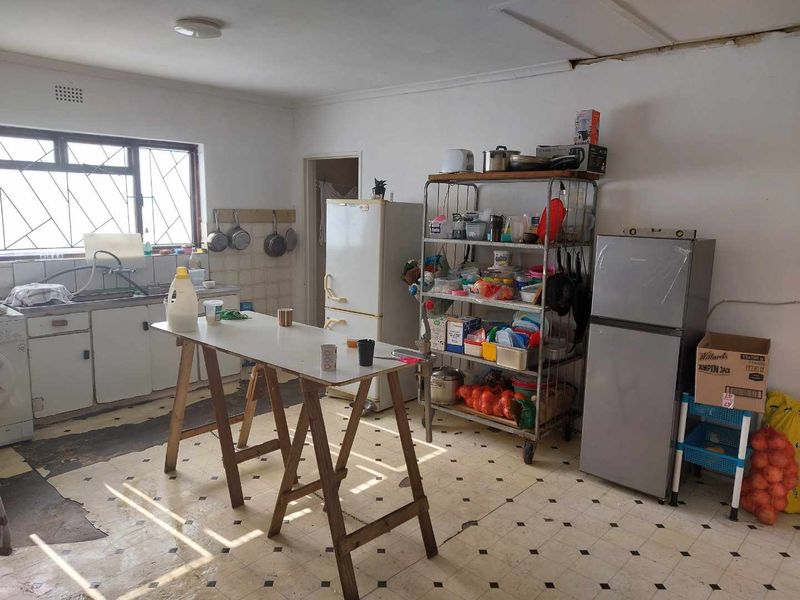 A dated kitchen space featuring a basic sink area, tiled splashback, and worn vinyl flooring, offering significant potential for a modern renovation.
