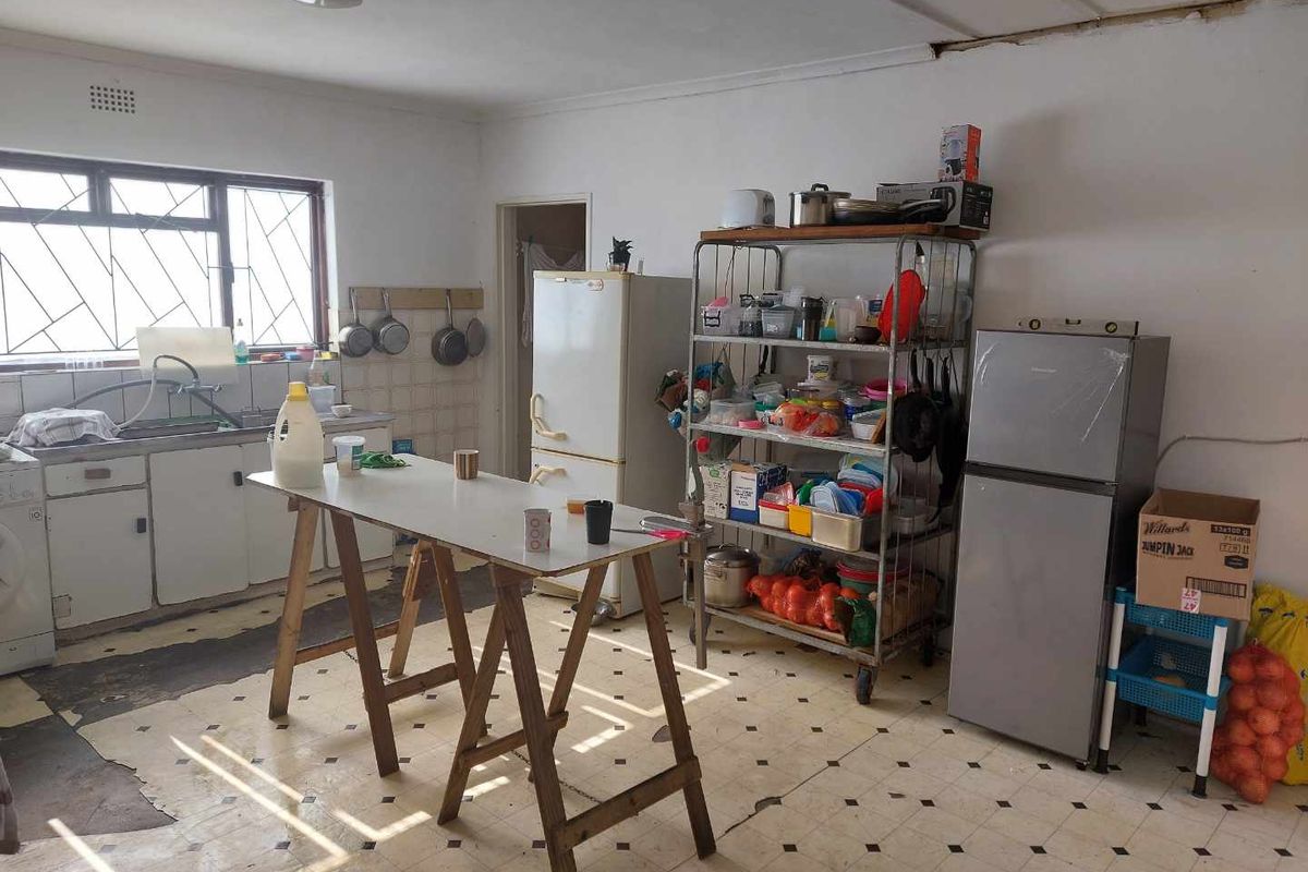 A dated kitchen space featuring a basic sink area, tiled splashback, and worn vinyl flooring, offering significant potential for a modern renovation.