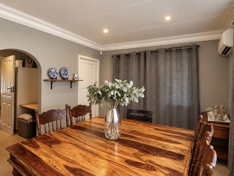 A well-maintained dining room featuring an arched doorway, recessed ceiling lighting, and a wall-mounted split-system air conditioning unit.
