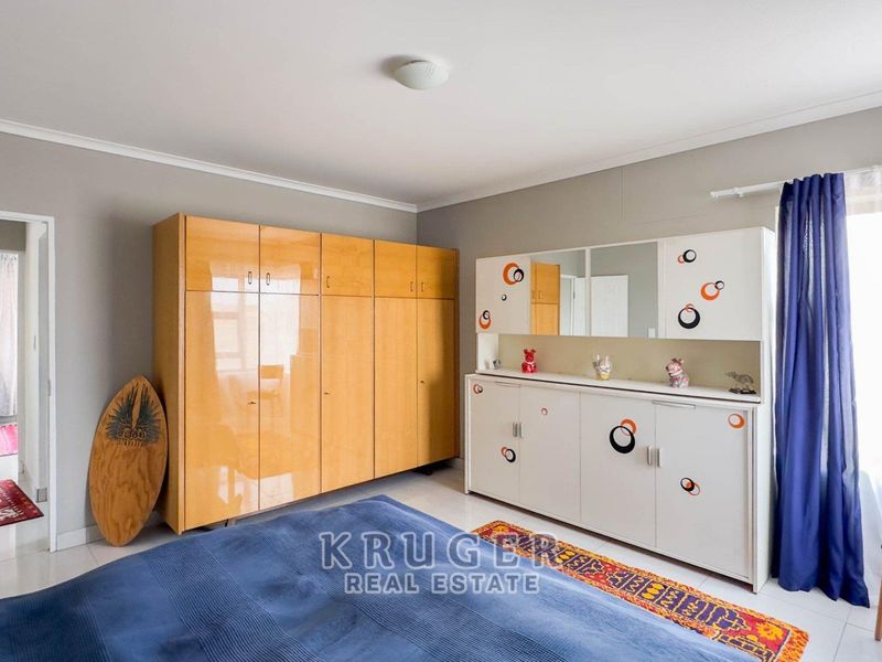 A bedroom featuring built-in cupboards, tiled flooring, and neutral wall finishes, offering a functional space with ample storage.