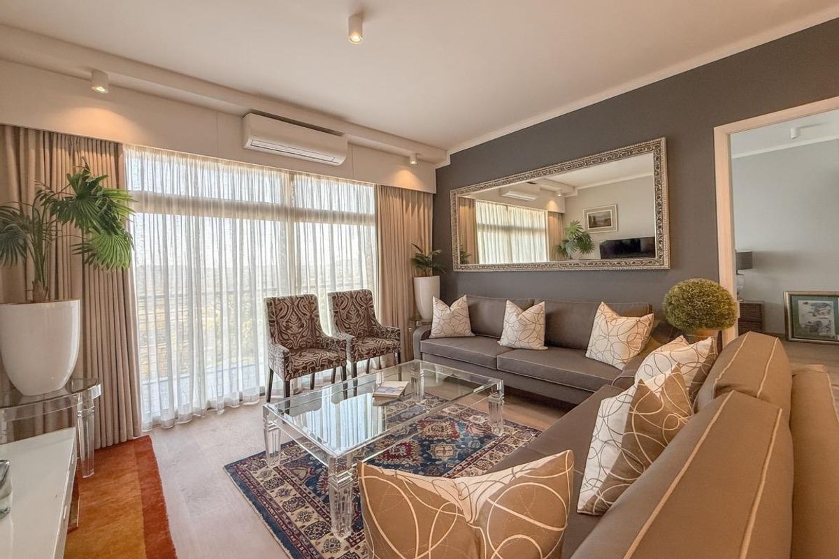 A well-maintained living room featuring a split-system air conditioner, recessed lighting, and large sliding glass doors leading to a balcony.