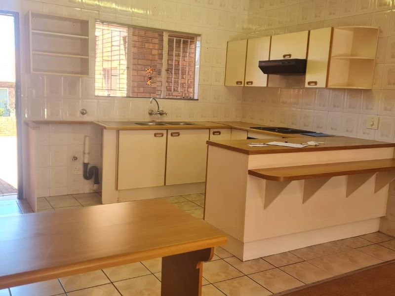 A functional kitchen featuring built-in cabinetry, a breakfast bar, and tiled finishes, offering a practical layout with potential for modern updates.