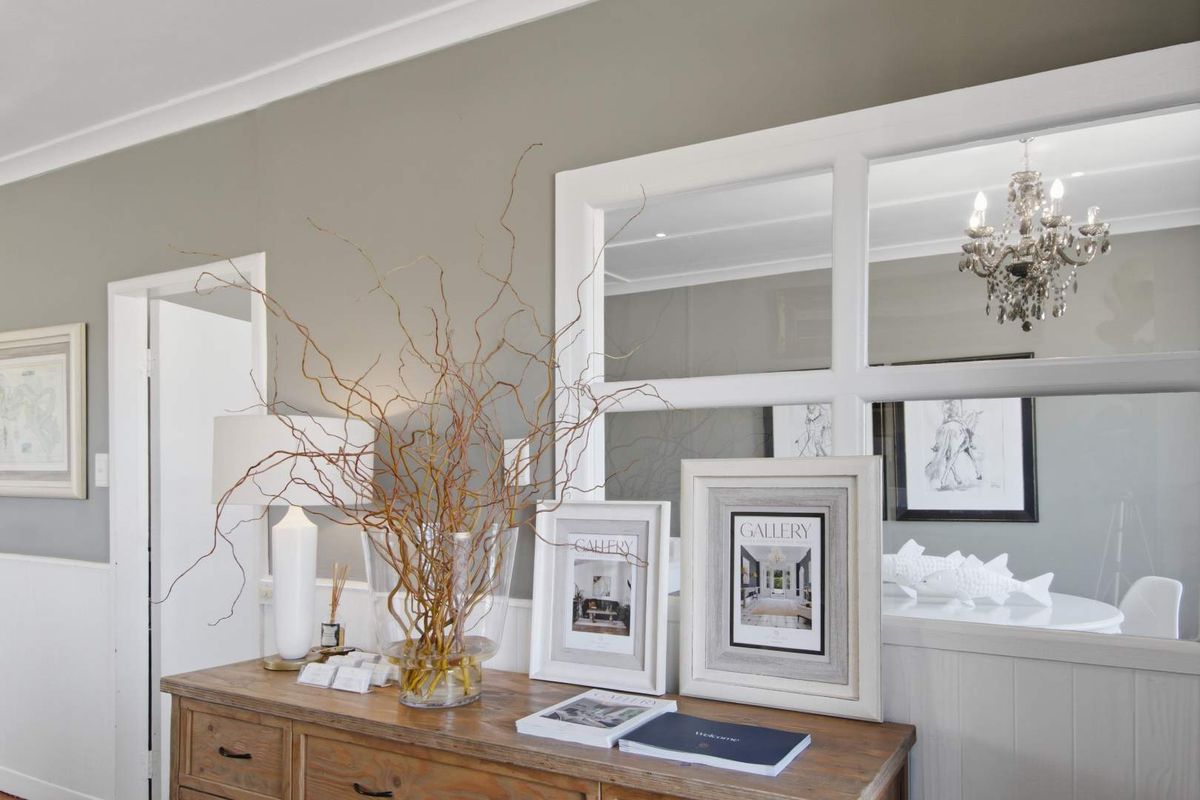 A well-maintained living area featuring classic wainscoting, crown molding, and a decorative internal window partition.
