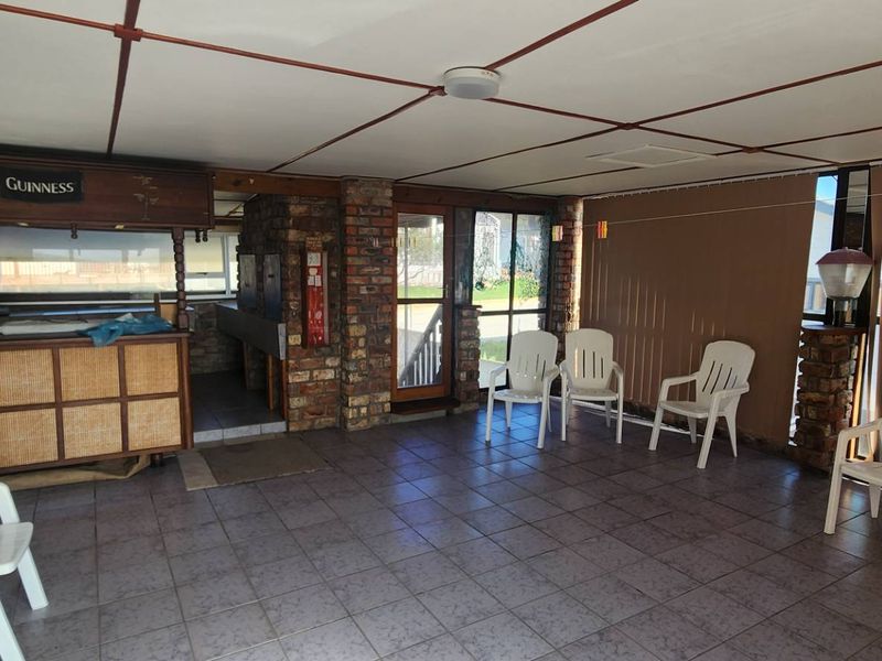 Covered patio area featuring a built-in bar, exposed brick walls, tiled flooring, and direct access to the garden through a glass door.
