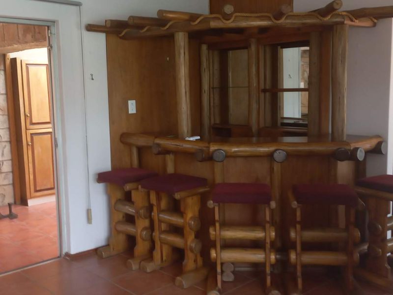 A dedicated bar area featuring a rustic built-in wooden counter, tiled flooring, and direct access to an adjacent room through a sliding glass door.