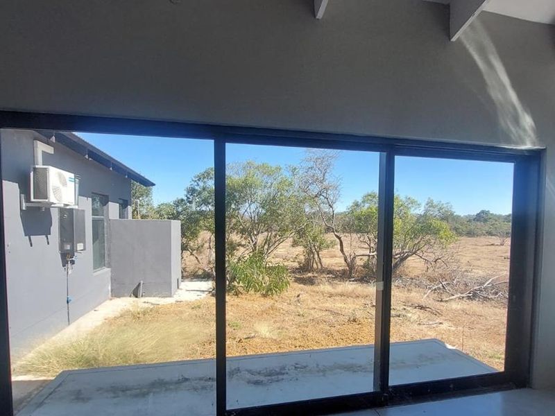 Spacious living area featuring large sliding glass doors, exposed ceiling beams, and polished concrete floors, offering a bright and modern open-plan feel.