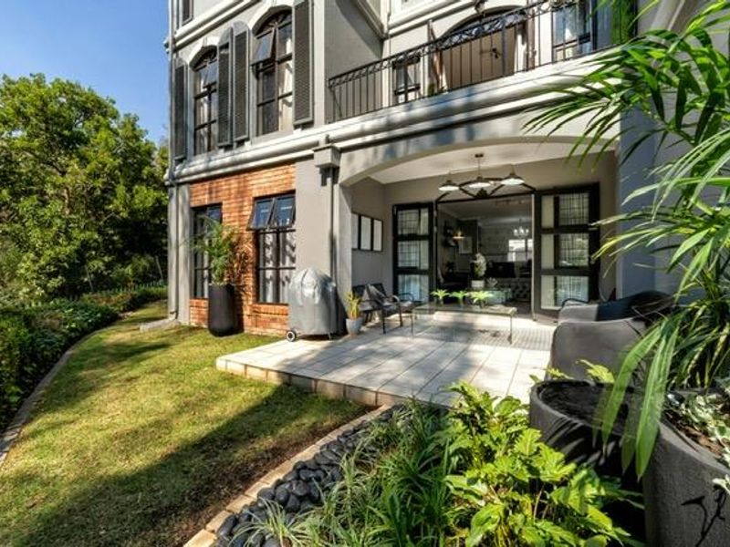 A well-maintained rear patio area featuring tiled flooring, brick accents, and direct access to the interior through large sliding glass doors.