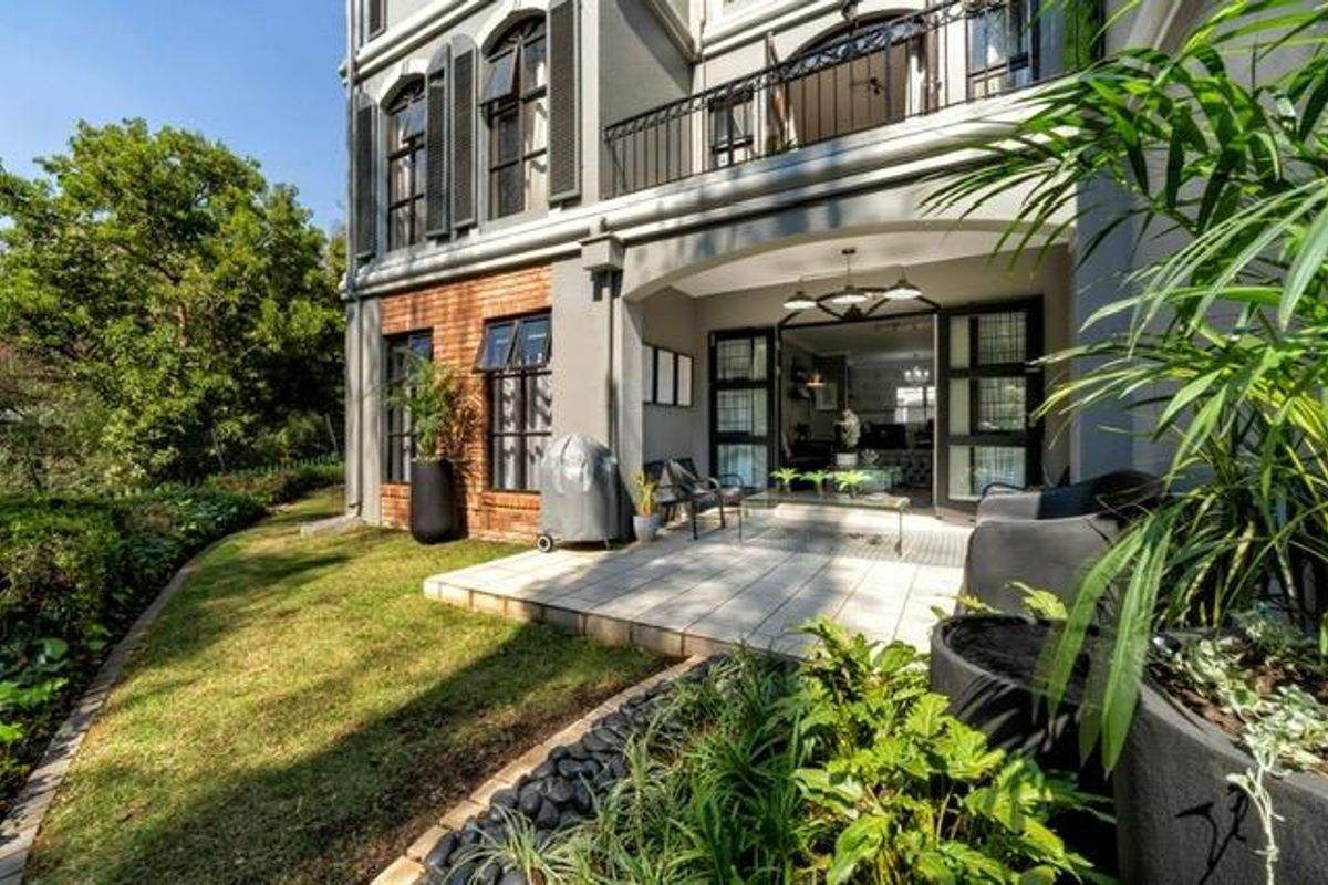 A well-maintained rear patio area featuring tiled flooring, brick accents, and direct access to the interior through large sliding glass doors.
