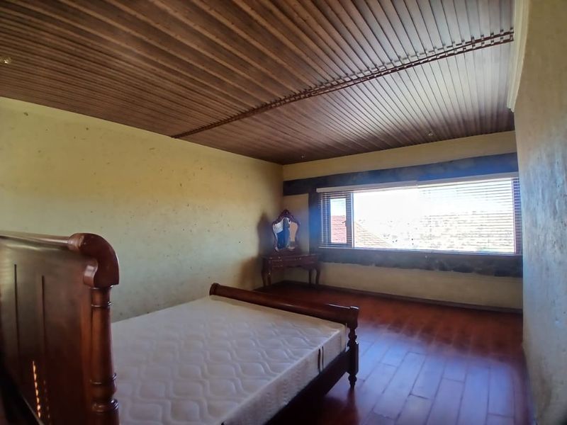 A bedroom featuring a wooden ceiling, laminate flooring, and a large horizontal window providing natural light.