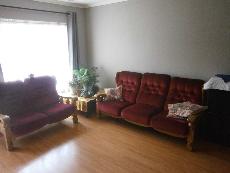 A living room featuring laminate flooring and a large window with a curtain rod, providing natural light to the space.