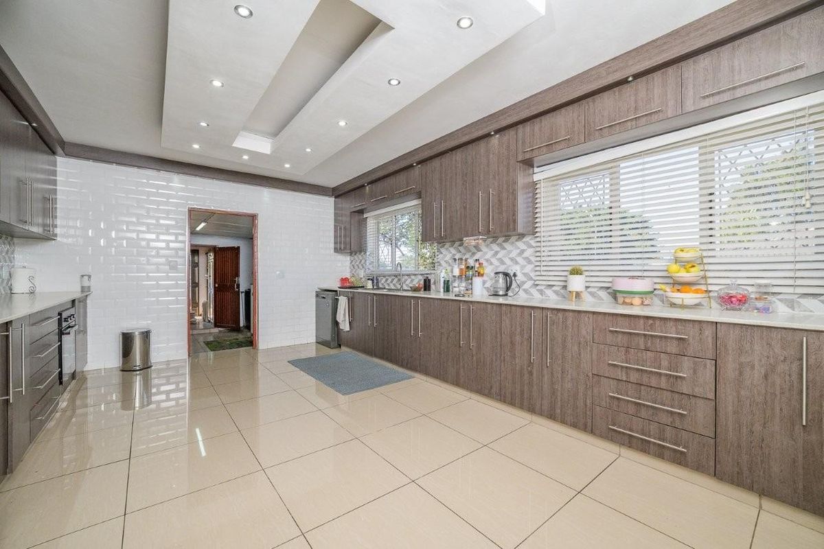 Modern kitchen featuring extensive wood-grain cabinetry, stone countertops, subway tile backsplash, and a stylish drop ceiling with recessed lighting.