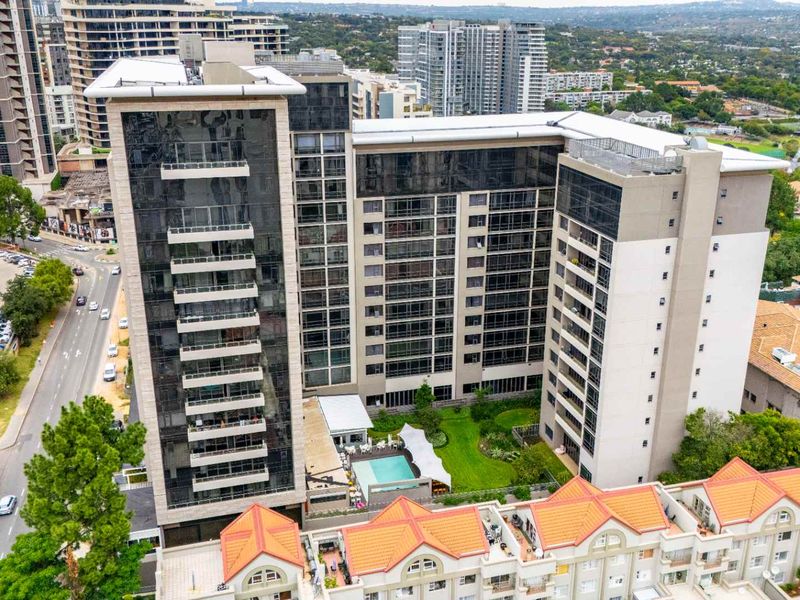 Aerial view of a modern high-rise penthouse complex featuring a swimming pool, landscaped garden area, and multiple balconies.