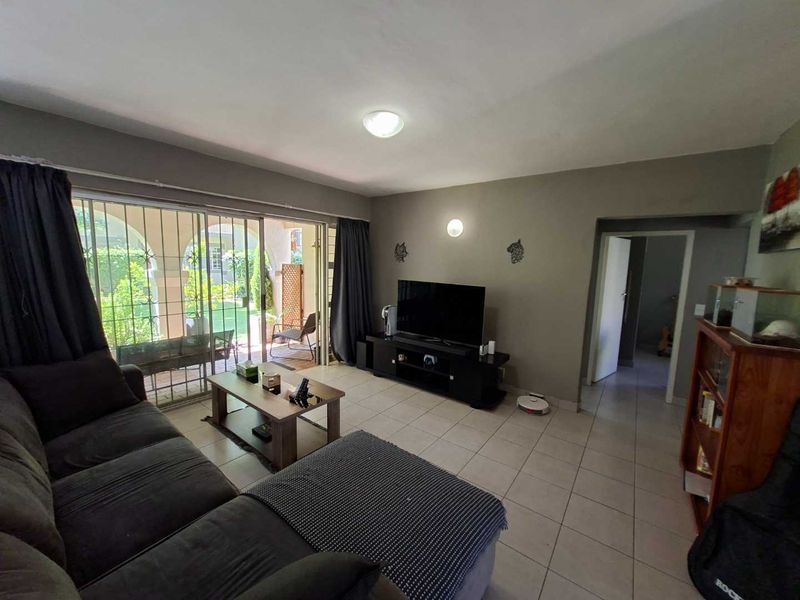 A living room featuring tiled flooring, neutral wall tones, and a large sliding glass door providing access to an outdoor patio area.