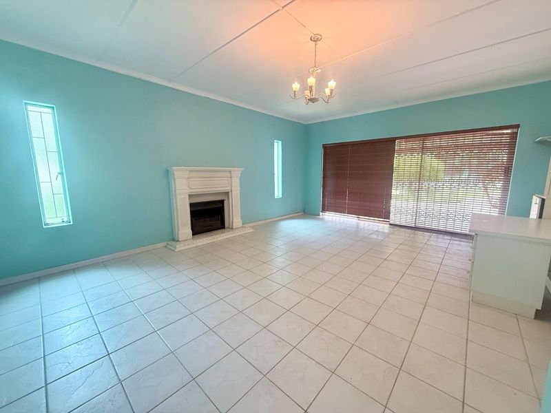 Spacious living room featuring tiled flooring, a classic fireplace, and large sliding glass doors that provide access to the outdoor area.