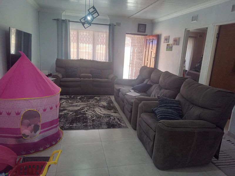A functional living room featuring tiled flooring, a window with security bars, and a security gate leading to the exterior.
