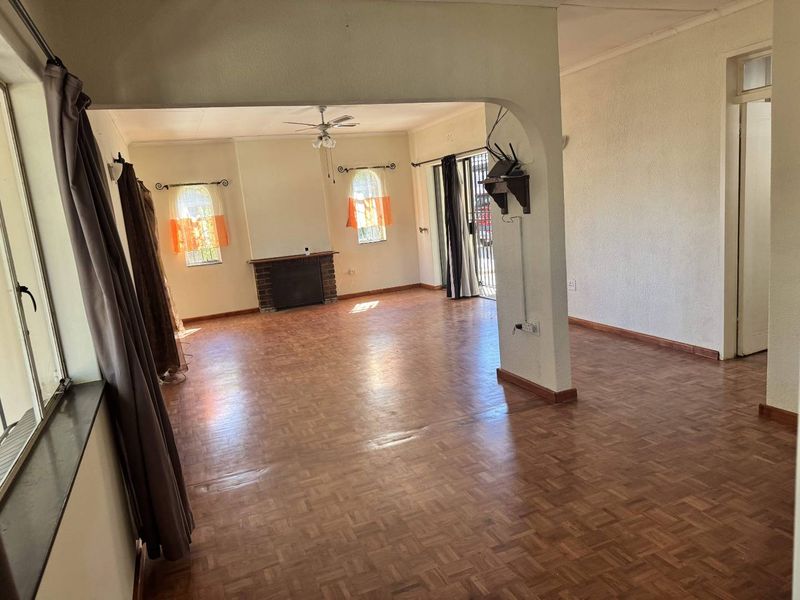 Spacious living area featuring classic parquet flooring, a brick fireplace, and an arched transition to an adjacent space with sliding door access.