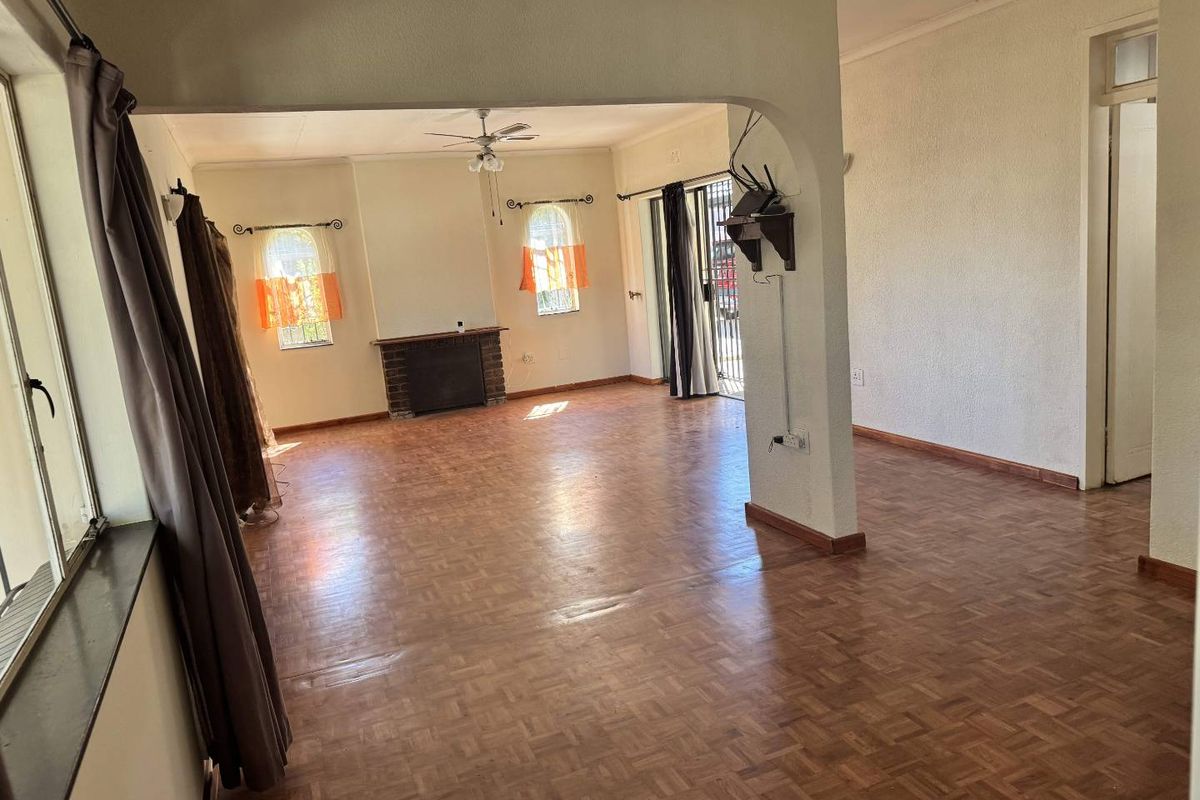 Spacious living area featuring classic parquet flooring, a brick fireplace, and an arched transition to an adjacent space with sliding door access.