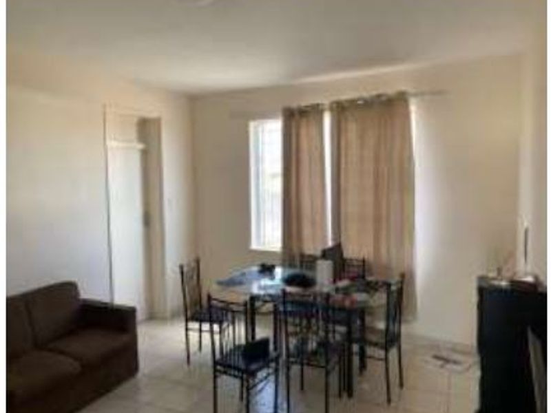 An open-plan living and dining area featuring tiled flooring and a window with a curtain rod, offering a functional layout for daily living.