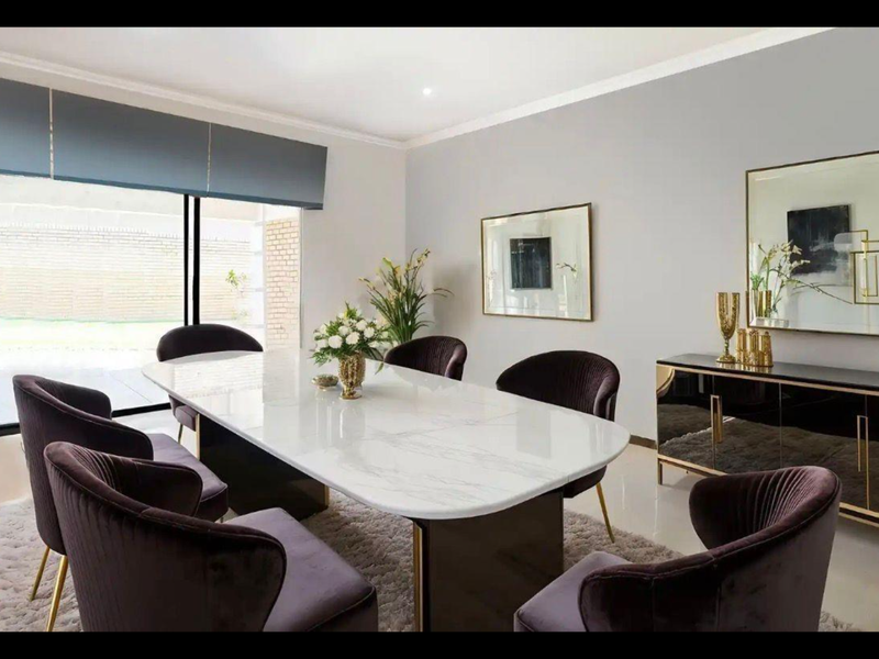 A well-lit, modern dining room featuring tiled floors, elegant cornicing, and large sliding glass doors that provide access to the outdoor area.