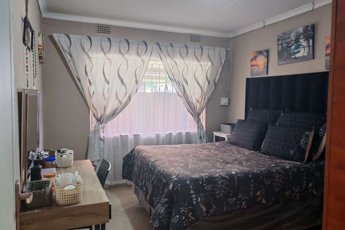 A functional bedroom featuring tiled flooring, neutral wall tones, and built-in ventilation grilles, providing a comfortable and well-maintained living space.