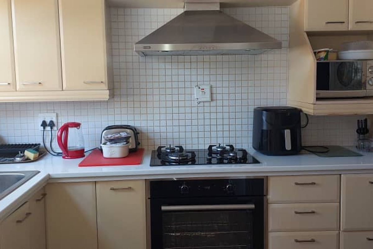 A functional kitchen featuring built-in cabinetry, a gas hob, an integrated oven, a stainless steel extractor fan, and a tiled backsplash.
