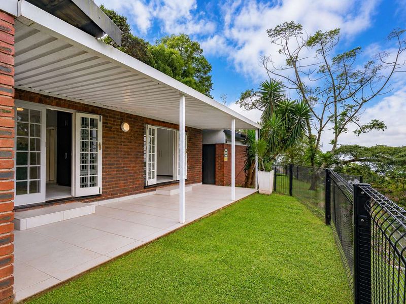 A well-maintained covered patio featuring tiled flooring and brick exterior, providing seamless access to the garden and outdoor area.